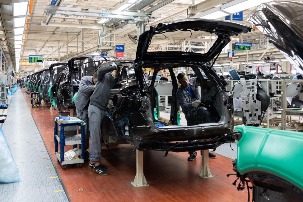 three men working on car bodies on the assembly line for production