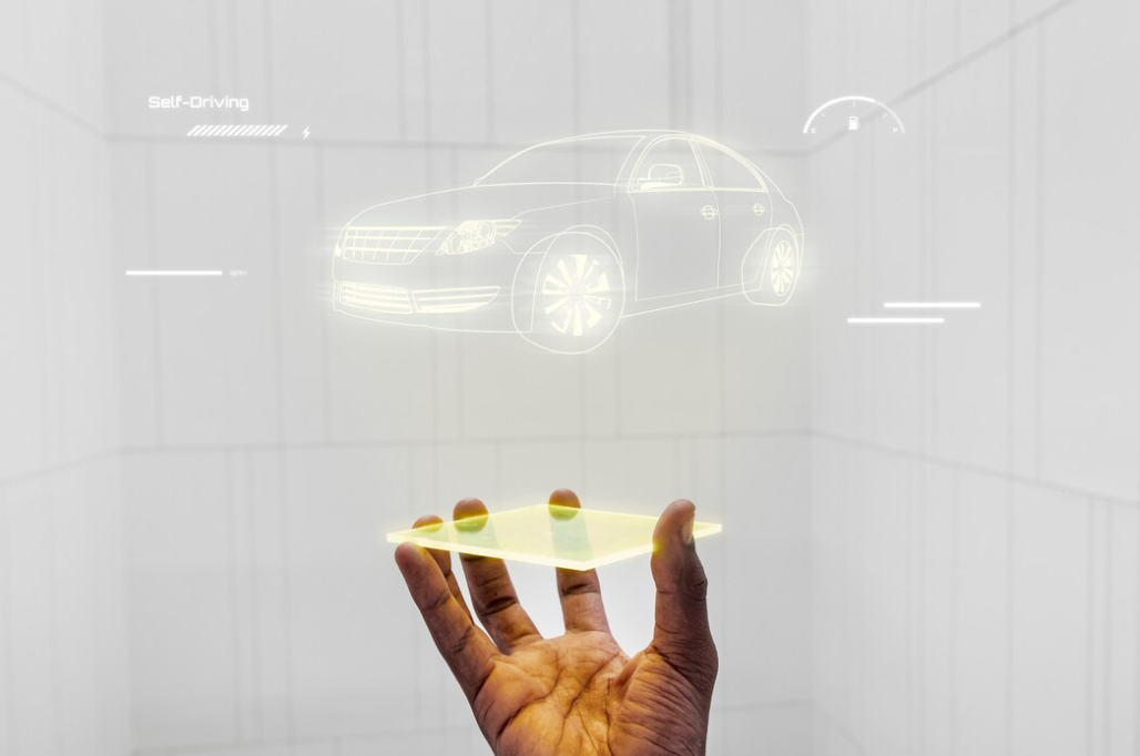 A holographic projection of a self-driving car concept above a human hand