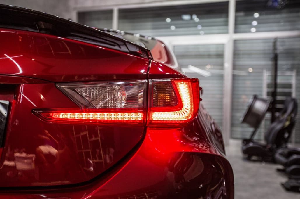 Back red lights of a red sports car, the windows with blinds behind on the background